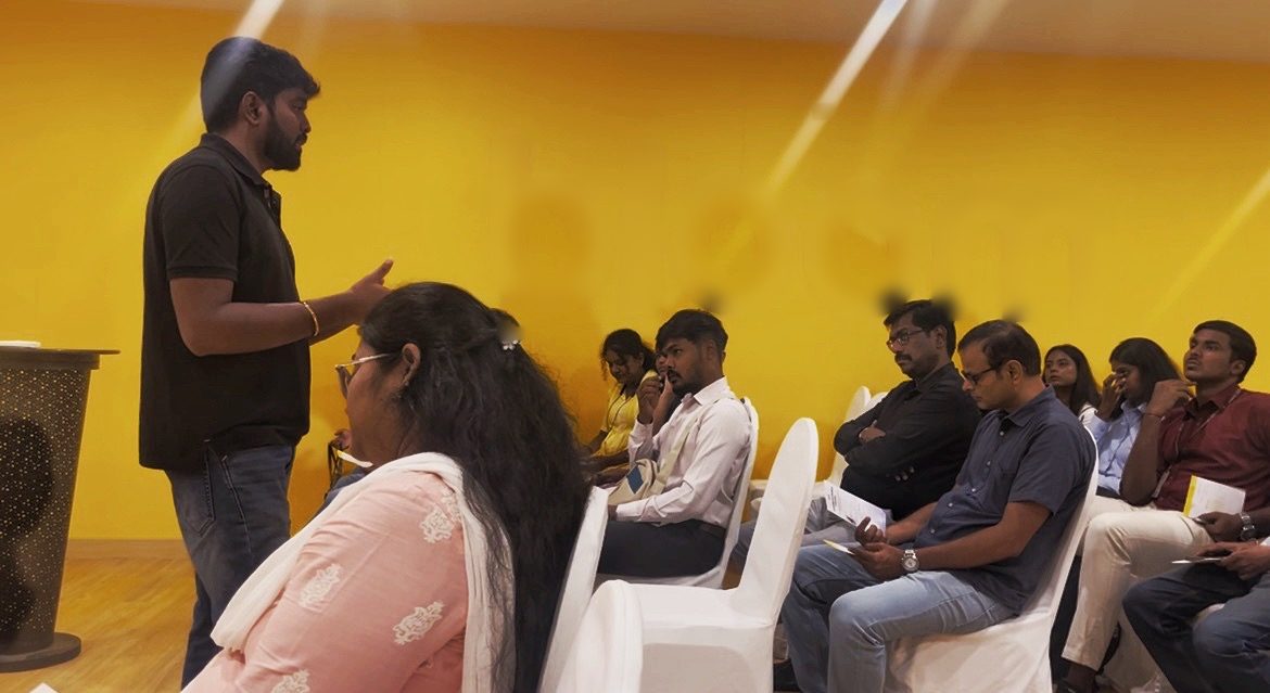 Chanakian answering questions from an audience in front of a yellow wall